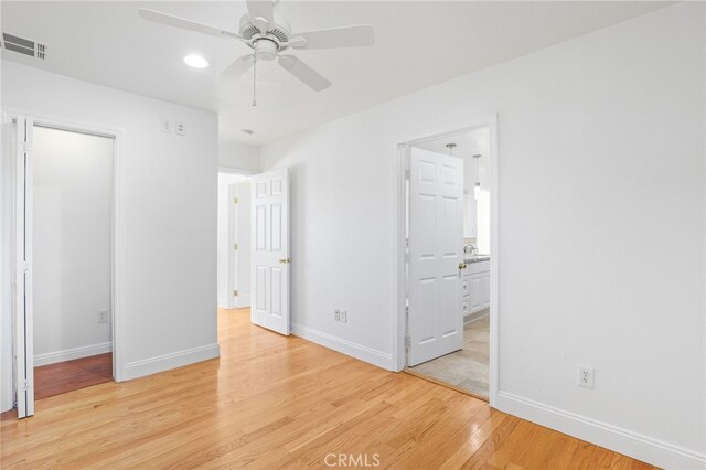 unfurnished bedroom with light wood-type flooring, ceiling fan, and connected bathroom