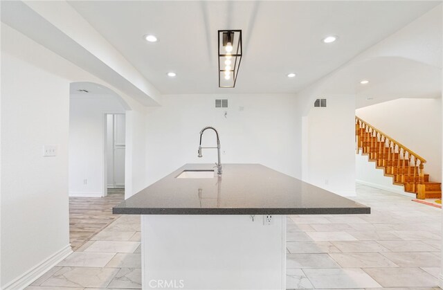 kitchen featuring a kitchen bar, sink, and a large island with sink