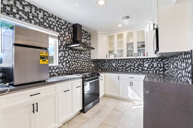 kitchen featuring gas stove, tasteful backsplash, stainless steel refrigerator, white cabinets, and wall chimney range hood