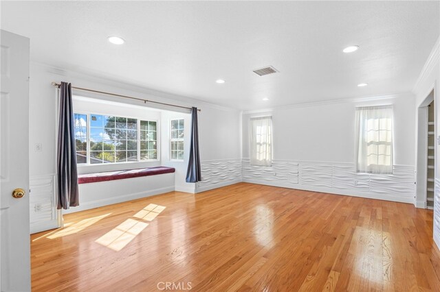 spare room with plenty of natural light, ornamental molding, and hardwood / wood-style floors