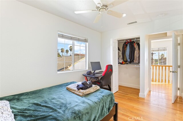 bedroom with ceiling fan, light hardwood / wood-style floors, multiple windows, and a closet