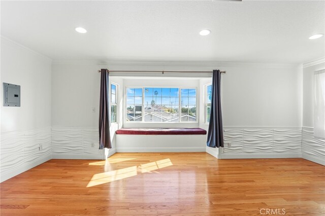 empty room with hardwood / wood-style floors, crown molding, and electric panel