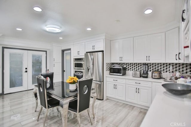 kitchen with white cabinets, french doors, decorative backsplash, and stainless steel appliances