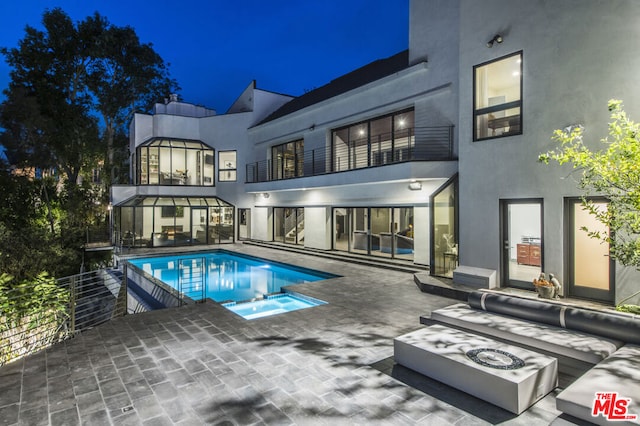 back house at night with an outdoor fire pit and a patio