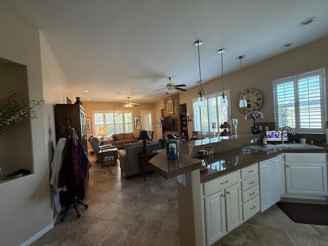 kitchen with ceiling fan, dishwasher, kitchen peninsula, plenty of natural light, and white cabinets