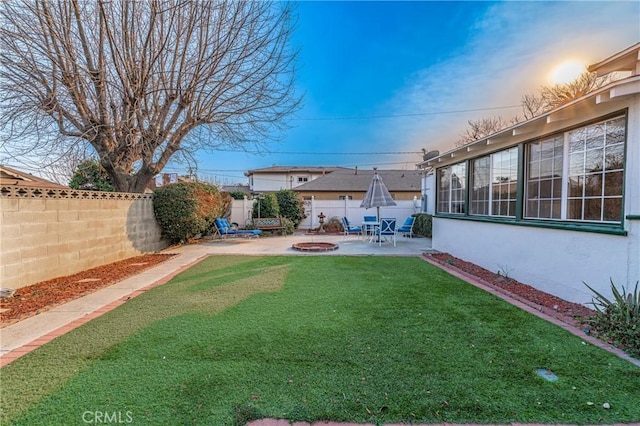 yard at dusk featuring a patio area and a fire pit