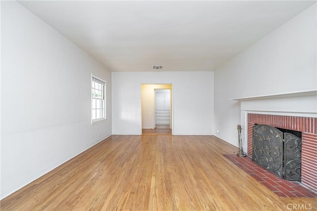 unfurnished living room featuring a brick fireplace and light hardwood / wood-style flooring