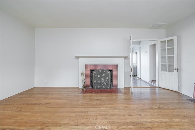 unfurnished living room featuring a brick fireplace and light hardwood / wood-style flooring