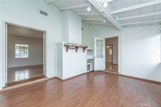 unfurnished living room with wood-type flooring and vaulted ceiling with beams