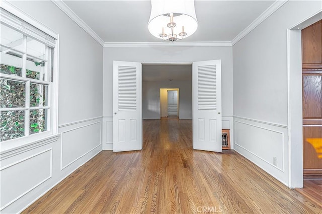 unfurnished dining area featuring a notable chandelier, ornamental molding, and hardwood / wood-style floors