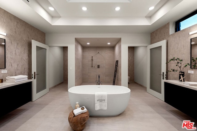 bathroom featuring a raised ceiling, vanity, and shower with separate bathtub