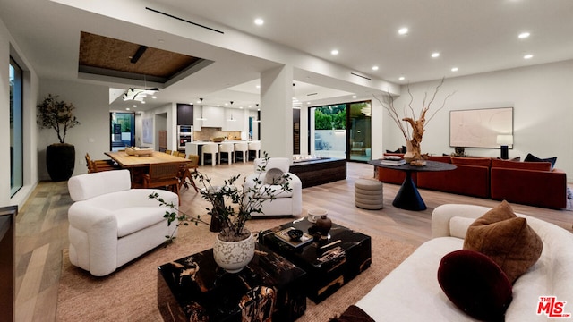 living room with a raised ceiling and light wood-type flooring