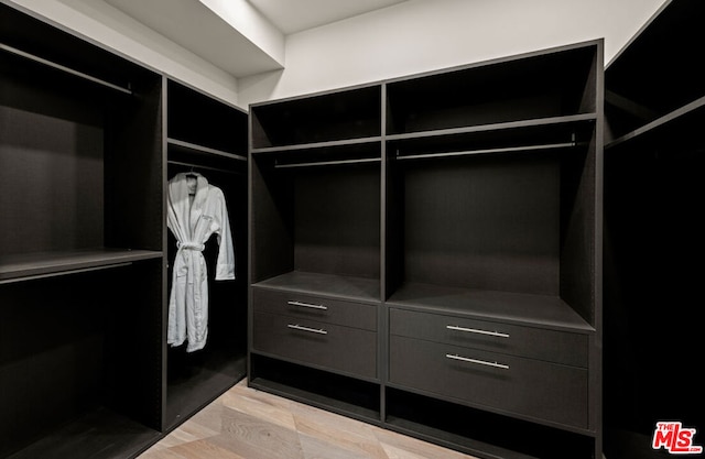 walk in closet with light hardwood / wood-style flooring