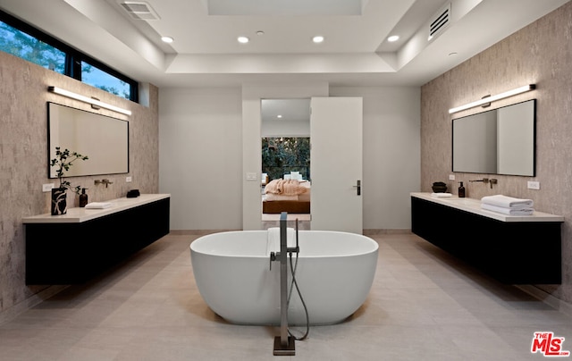 bathroom with a bathtub, vanity, and a raised ceiling