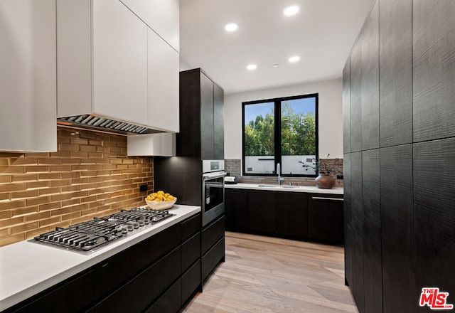 kitchen featuring backsplash, light hardwood / wood-style floors, sink, stainless steel appliances, and white cabinets