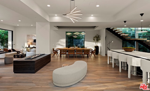 living room with wood-type flooring, a tray ceiling, and an inviting chandelier