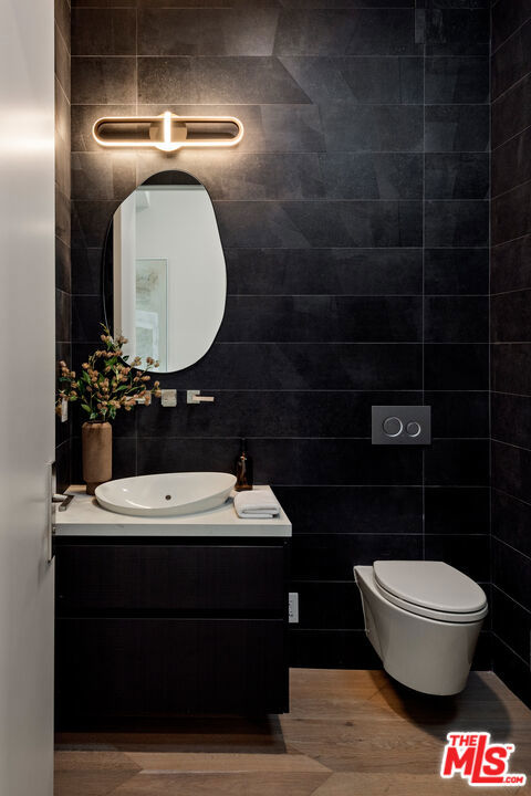 bathroom featuring toilet, tile walls, wood-type flooring, and vanity