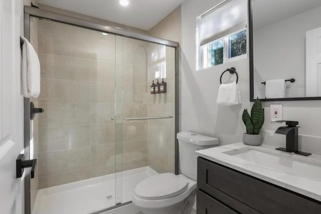 bathroom with vanity, toilet, and a shower with shower door