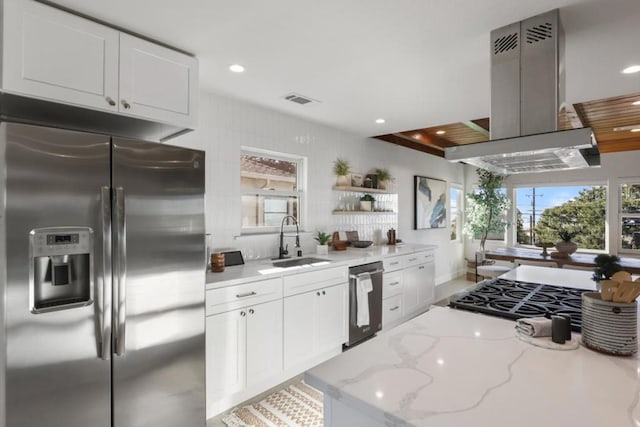 kitchen with white cabinetry, sink, island exhaust hood, light stone counters, and stainless steel appliances