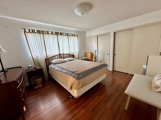 bedroom with multiple closets and dark wood-type flooring