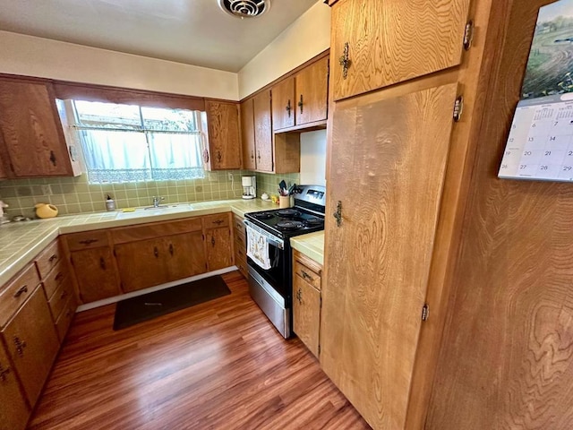 kitchen featuring electric stove, tile countertops, tasteful backsplash, and light wood-type flooring