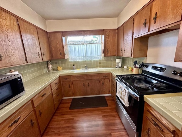 kitchen featuring stainless steel appliances, tasteful backsplash, dark hardwood / wood-style floors, and tile counters