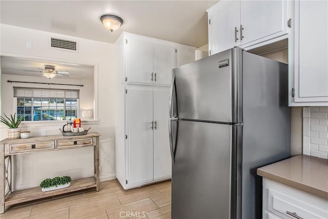 kitchen with ceiling fan, white cabinets, and stainless steel fridge