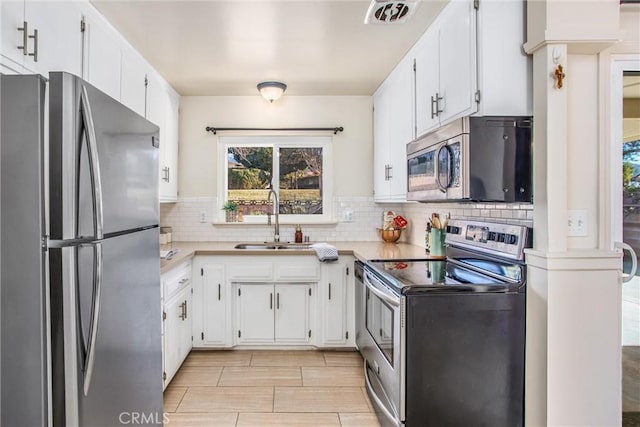 kitchen with white cabinets, backsplash, appliances with stainless steel finishes, and sink