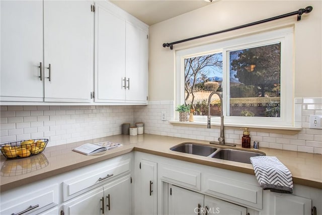 kitchen featuring sink, backsplash, and white cabinets