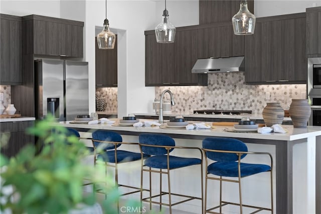 kitchen with backsplash, appliances with stainless steel finishes, a kitchen breakfast bar, and dark brown cabinetry