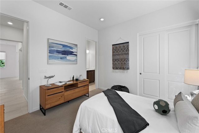 carpeted bedroom featuring a closet and ensuite bath