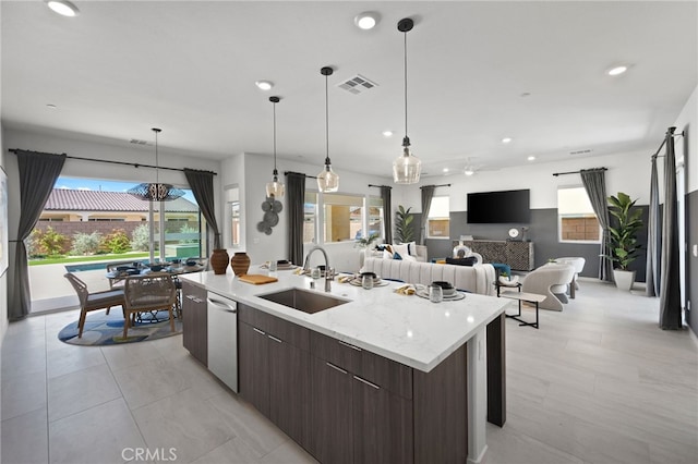 kitchen featuring sink, dark brown cabinetry, a healthy amount of sunlight, and an island with sink