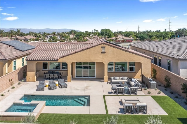 back of property featuring a patio area, a swimming pool with hot tub, a mountain view, and a bar