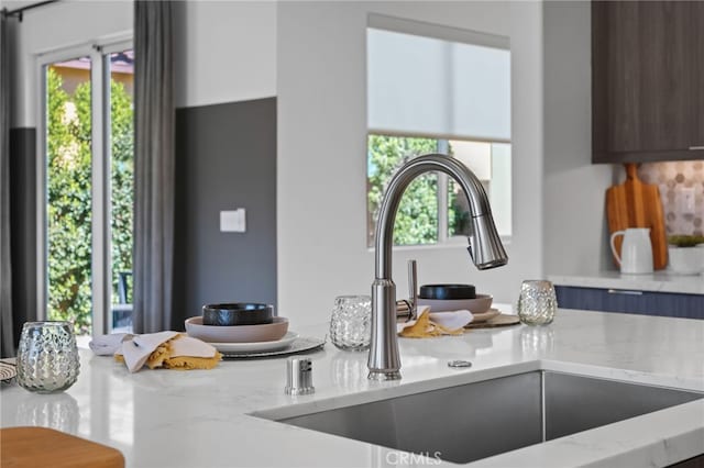 kitchen featuring plenty of natural light, sink, and light stone counters