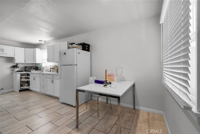 kitchen with tasteful backsplash, white cabinets, sink, and white fridge