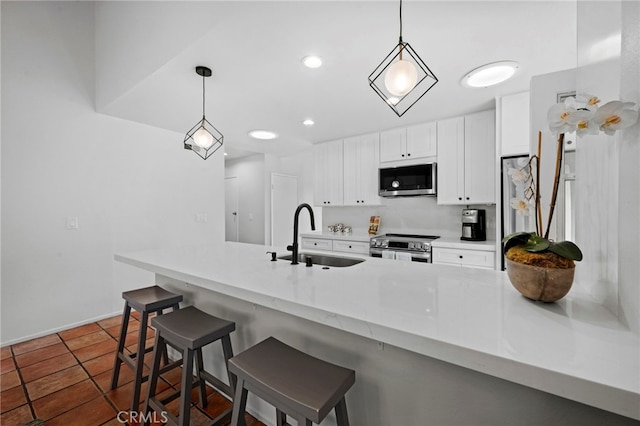 kitchen with decorative light fixtures, a breakfast bar, sink, stainless steel appliances, and white cabinets