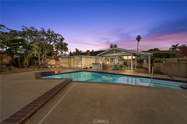 pool at dusk featuring a patio area