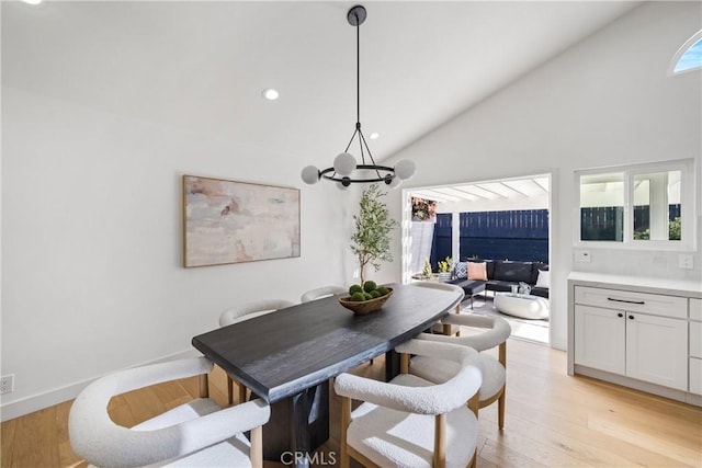 dining area featuring lofted ceiling, light hardwood / wood-style floors, plenty of natural light, and a notable chandelier