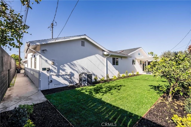 back of property with central AC unit and a yard