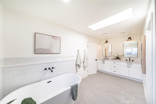 bathroom with a tub to relax in, vanity, a skylight, and tile patterned floors