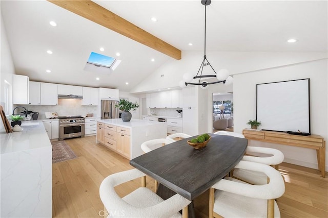 dining room with light hardwood / wood-style floors, beam ceiling, sink, a skylight, and a chandelier