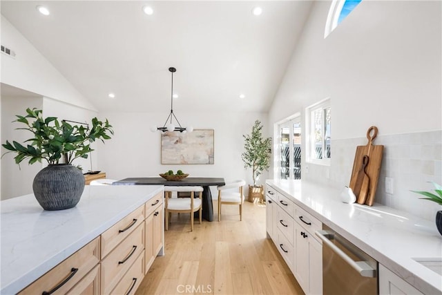 kitchen with pendant lighting, light hardwood / wood-style floors, light brown cabinetry, high vaulted ceiling, and stainless steel dishwasher