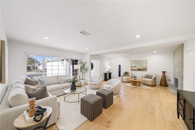 living room featuring a tile fireplace and light hardwood / wood-style floors