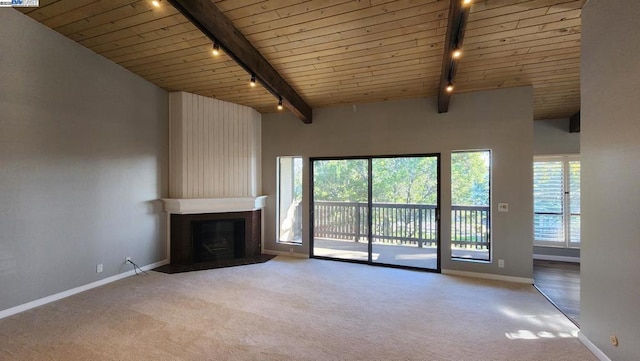 unfurnished living room with track lighting, vaulted ceiling with beams, a fireplace, light colored carpet, and wooden ceiling