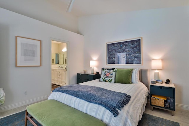 bedroom with ensuite bathroom, dark wood-type flooring, and sink