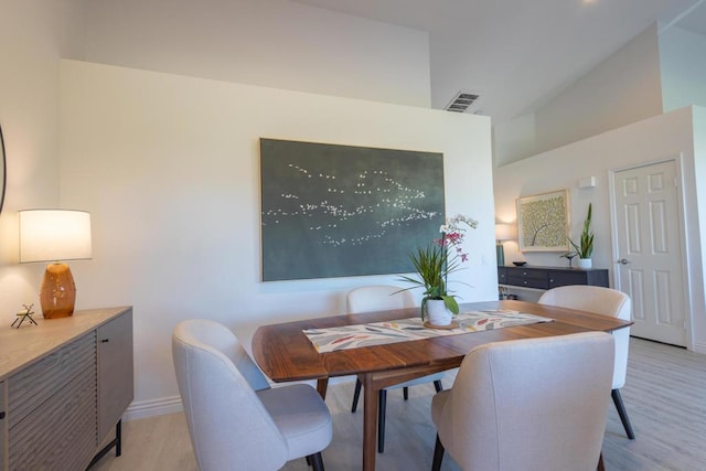 dining room with vaulted ceiling and light hardwood / wood-style flooring