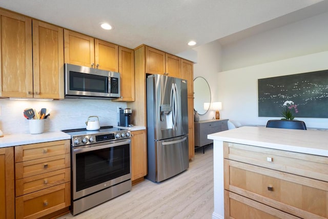 kitchen featuring appliances with stainless steel finishes, light hardwood / wood-style flooring, and tasteful backsplash