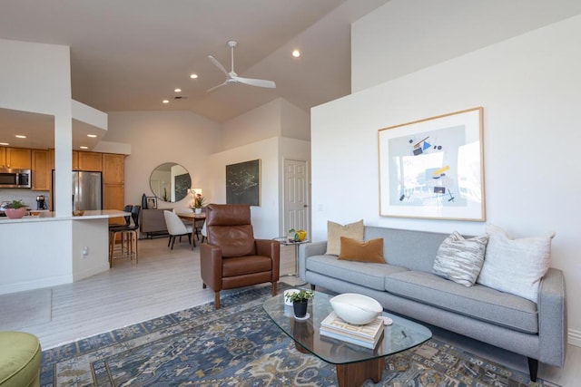 living room featuring ceiling fan, vaulted ceiling, and light wood-type flooring