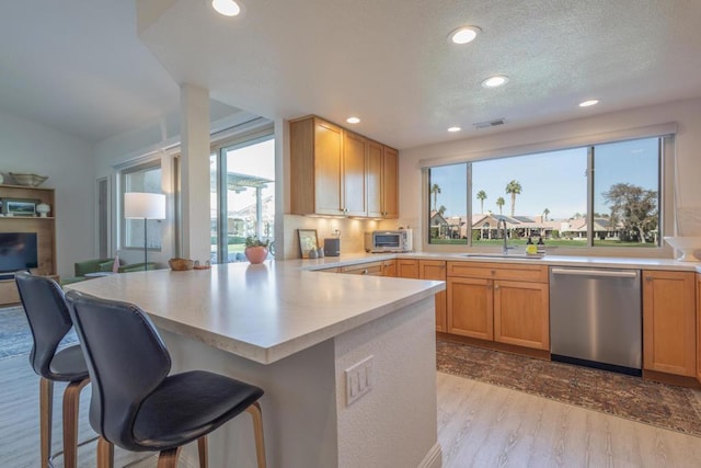 kitchen featuring sink, dishwasher, a kitchen breakfast bar, and light hardwood / wood-style flooring