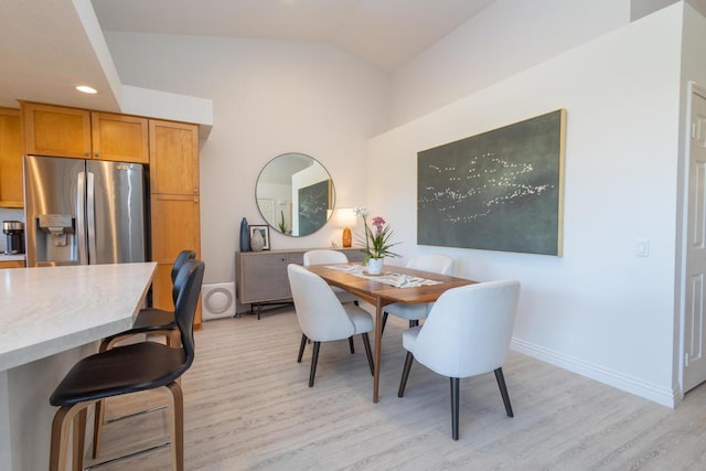 dining room with light hardwood / wood-style flooring and vaulted ceiling